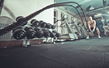 Antrenman konsepti. Jimnastik salonundaki iplerle çalışan güçlü çekici bir genç adam. İple antrenman