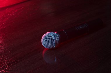 Karaoke. Gece hayatı konsepti. Mikrofonlar ahşap bir masanın üzerinde. Koyu kırmızı neon ışık