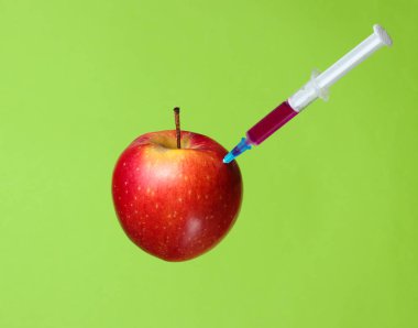 Genetiği değiştirilmiş Kırmızı Elma yeşil arka plan üzerinde şırıngalar ile. Tıbbi Şırınga elma Gdo enjekte