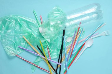 Kirlilik plastik ve polietilen çevre kavramı. Selofan torbası, plastik şişe, tek çatal ve kaşık, arka planda kokteyl tüpleri. Üstte görüntü