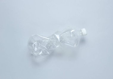 Minimalist ekolojik kavram. Gri arka planda buruşuk plastik şişe. Çevre plastik kirliliği