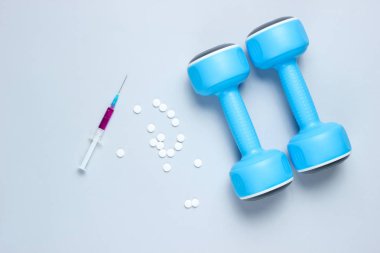 Sporda doping. Anabolik steroid. Spor Eczanesi. Plastik halterler, şırıngalar, gri arka plandaki haplar. Üstte görüntü.