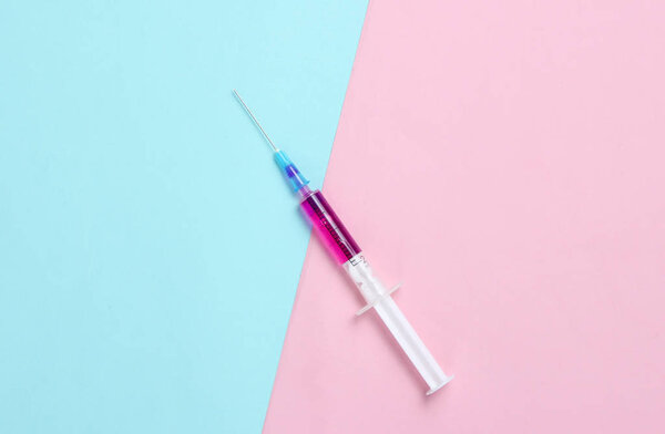 Minimalism medical concept, injection, vaccination. Syringe with purple liquid on blue pink pastel background.