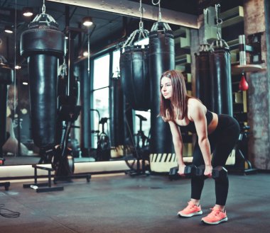 Kalça eğitimi. Sporda Fit kadın spor salonunda dumbbell ile deadlift egzersiz yapıyor giymek