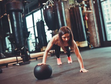Karanlık spor salonunda şınav çeken bir kadın.