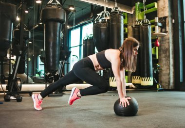 Spor salonunda tıp topuyla çalışan genç bir kadın. İşlevsel eğitim, çapraz uyum