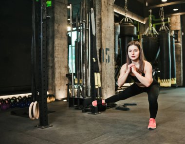 Spor salonunda Trx 'in bacakları için egzersiz yapan genç bir kadın. Fonksiyonel eğitim