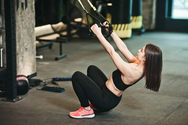 Fit woman doing exercise with fitness strap at gym. Workout, functional training. Sports lifestyle