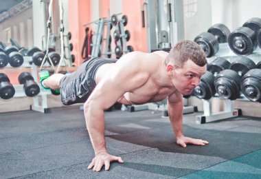 Spor salonunda halatlar üzerinde bacaklar ile katta şınav yapıyor Atletik adam