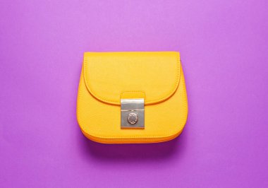 Mor arka planda sarı deri mini çanta. Minimalizm moda kavramı. Üst görünüm