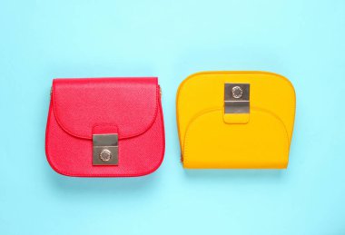 Kırmızı ve sarı, mavi arka planda iki deri mini çanta. Minimalizm moda kavramı. Üst görünüm