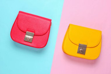 Kırmızı ve sarı, pastel renkli arka planda iki deri mini çanta. Minimalizm moda kavramı. Üst görünüm