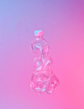 Minimalizm çevre kirliliği kavramı. Kırışmış plastik şişe neon kırmızı ışıkta
