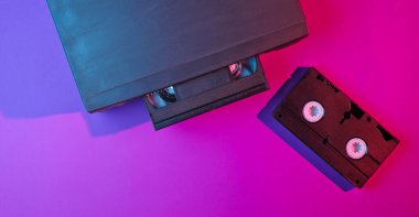 Retro dalga, minimalizm 80 'ler konsepti. Vhs kaseti olan video oynatıcı, neon ışık. Gece hayatı. Üst görünüm