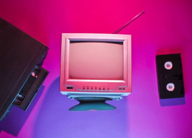 Retro dalga, 80 'lerin konsepti. Video oynatıcı, video kaset, eski televizyon, neon lamba. Üst manzara, düz uzanma