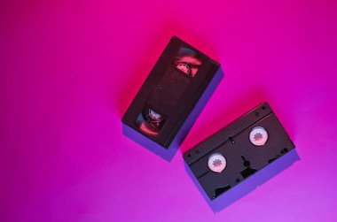 Retro dalga stili iki video kaset, üzerinde pembe-mavi ışık var. 80 'ler. Üst görünüm