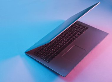 Canlı gradyan pembe neon ışıkları olan modern bir laptop. Ofis sürrealizmi konsepti.