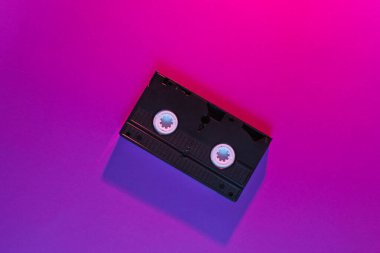 Retro dalga tarzı, neon pembe-mor ışıklı video kaset. 80 'ler. Üst görünüm