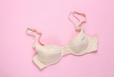 Pembe arka planda bej renkli kadın sütyeni. Üst görünüm, minimalizm
