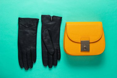 Kadın moda aksesuarları. Moda mini çanta, mavi arka planda deri eldivenler. Minimalizm