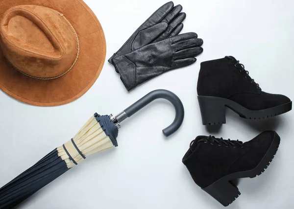 Autumn women\'s accessories. Leather gloves, felt hat, umbrella, boots on a white background. Top view.