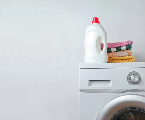 Bottle of washing gel, Stack of towels on washing machine. White background for copy space