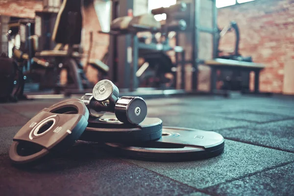 Halter, halterler salonun arka planında yere yatsın. Bedava ağırlık çalışması. Fonksiyonel güçlü eğitim