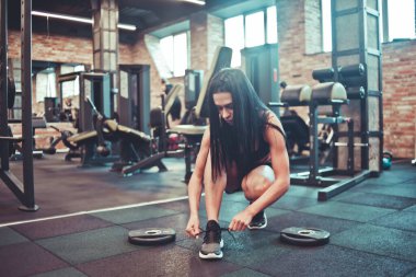 Çekici esmer kadın spor salonunda ayakkabılarını bağlıyor..