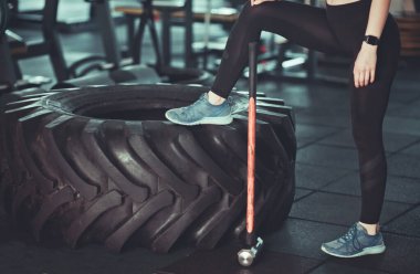 İşlevsel eğitim konsepti. Mola zamanı. Kadın bacaklarının kesilmiş fotoğrafı, büyük tekerlek, spor salonunda çekiç..