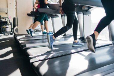 Koşu bandında koşan bir grup insan. Spor salonunda kilo vermek için kardiyo eğitimi..