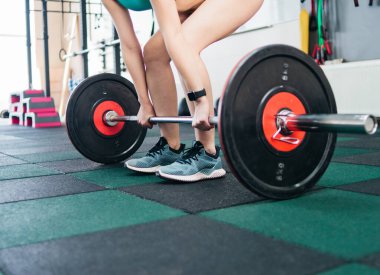 Güçlü, formda bir kadın spor salonunda halterle kaldırma yapıyor. Serbest ağırlık çalışması