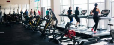 Koşu bandındaki insanlarla dolu bir spor salonunun bulanık fotoğrafı.