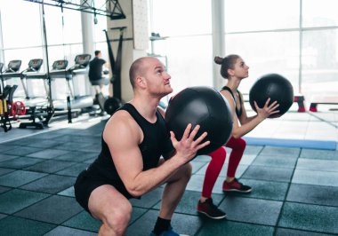 çift fonksiyonel eğitim. Sportif erkek ve formda kadın spor salonunda kettlebell ile egzersiz yapıyor.