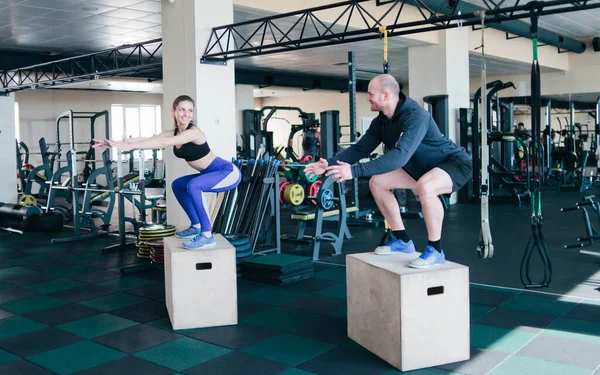 Couple functional training. Fitness man and woman jump on the wooden boxes in the gym