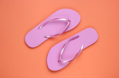 Mercan kağıdının arka planında son moda pembe parmak arası terlikler. Üst görünüm