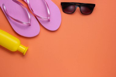 Yaz hala hayattır. Plaj aksesuarları. Modaya uygun plaj pembe terlikleri, güneş kremi şişesi, güneş gözlüğü, mercan kağıdında deniz kabuğu. Düz yatıyordu. Uzayı kopyala Üst görünüm