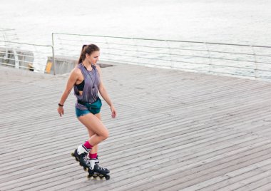 Plajda paten kayan genç ve çekici bir kadın.