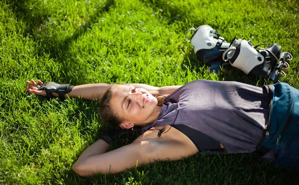Νεαρή Χαρούμενη Αθλήτρια Πατινέρ Ξαπλωμένη Στο Γρασίδι Του Πάρκου Και — Φωτογραφία Αρχείου