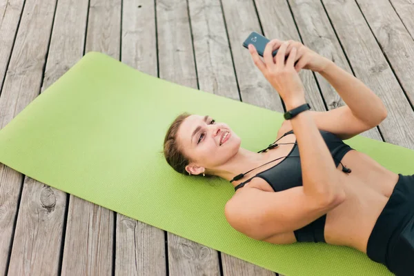 Jonge Vrolijke Sportvrouw Sportkleding Liggend Mat Houten Terras Maakt Gebruik — Stockfoto