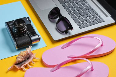 Yaz tatili. Yaz tatili gevşemesi. Laptop ve plaj aksesuarları sarı arka planda. Stüdyo kısa. Plaj nesnesi.