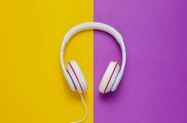 Mor sarı kağıt arka planda klasik beyaz kulaklıklar. Retro tarzı. 80 'ler. Popüler kültür. Üst Manzara. Asgari Müzik Konsepti