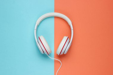 Renkli kağıt arka planda klasik beyaz kulaklıklar. Retro tarzı. 80 'ler. Popüler kültür. Üst Manzara. Asgari Müzik Konsepti