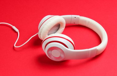 Kırmızı kağıt arka planda klasik beyaz kulaklıklar. Retro tarzı. 80 'ler. Popüler kültür. Müzik aşığı