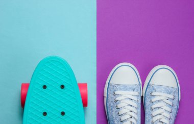 Mor mavi arka planda hippi spor ayakkabıları ve kaykay üstü görünümü. Minimalizm moda kavramı.