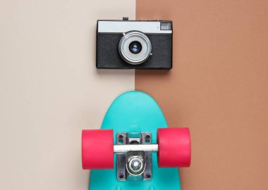 Retro set mavi kaykay ve renkli arka planda retro kamera. Stüdyo çekimi. Gençlik yaşam tarzı. Üst görünüm