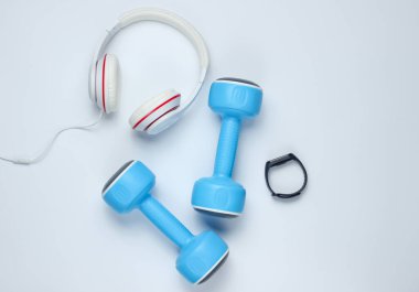 Dambıllar, akıllı bilezikler, beyaz arka planda kulaklıklar. Minimalist spor konsepti. Üst görünüm.