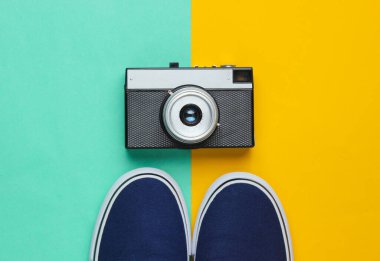 Hippi stili düz yatıyordu. Klasik spor ayakkabıları ve pastel renkli arka planda retro film kamerası. Üst görünüm