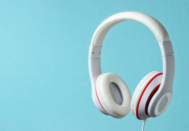 Beyaz klasik kulaklıklar mavi arka planda izole edilmiş. Retro tarzı. Minimalist müzik konsepti.