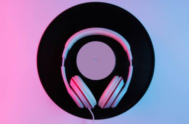 Retro tarzı müzik konsepti. Klasik kulaklıklar, gradyan pembe-neon ışıklı vinil plaklar. Popüler kültür. 80 'ler. Üst görünüm