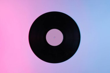 Retro tarzı müzik konsepti. Gradyan pembe-mavi neon ışıklı vinil plak. Popüler kültür. 70 'ler. Üst görünüm